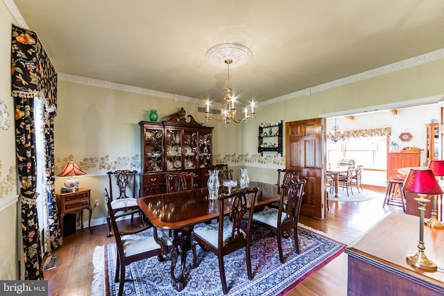 dining space with an inviting chandelier, crown molding, and hardwood / wood-style flooring