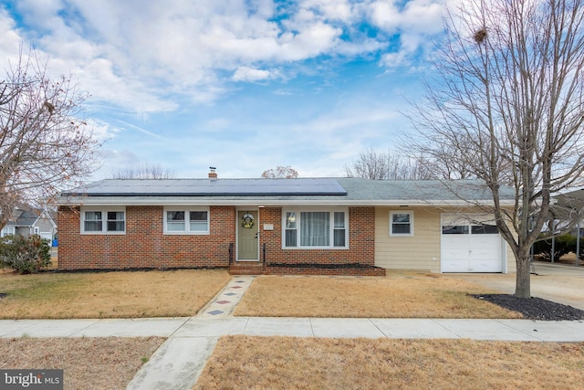 single story home with a front lawn, solar panels, and a garage