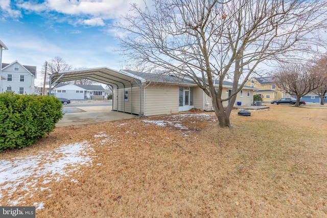 view of side of property with a carport and a lawn