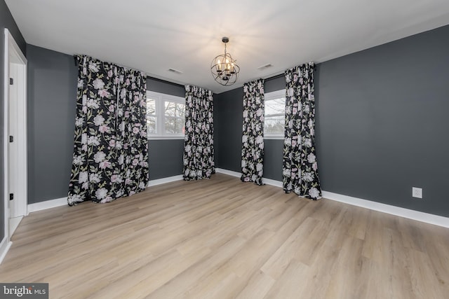 unfurnished room featuring light wood-type flooring and a notable chandelier