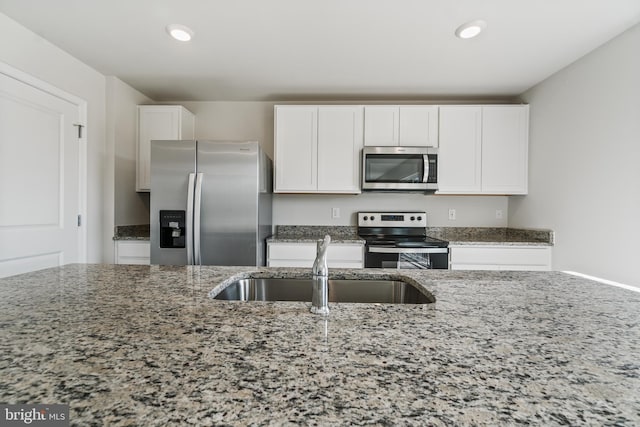 kitchen with sink, white cabinets, dark stone counters, and appliances with stainless steel finishes