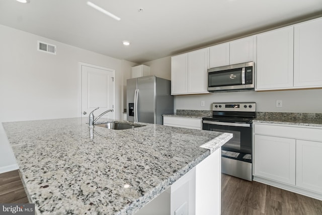 kitchen featuring stainless steel appliances, a kitchen island with sink, dark wood-type flooring, and sink