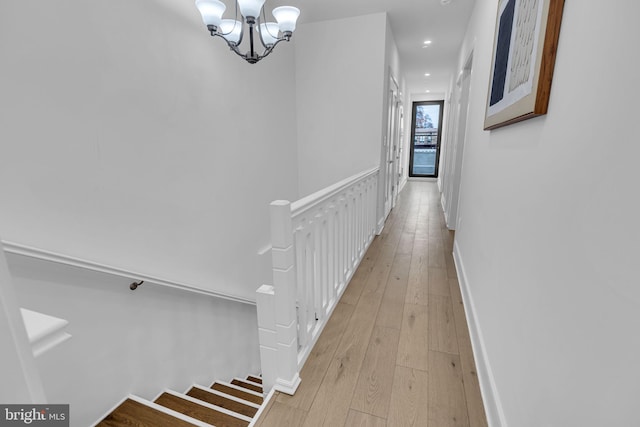 hallway with an inviting chandelier and light wood-type flooring