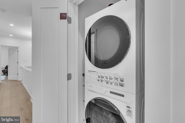 laundry room with stacked washer and dryer and light hardwood / wood-style flooring