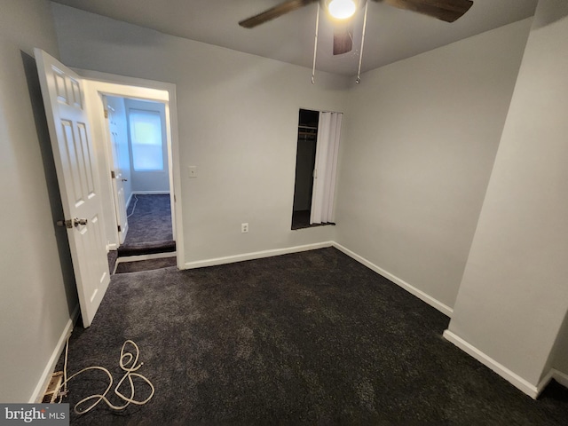 unfurnished room with dark colored carpet and ceiling fan