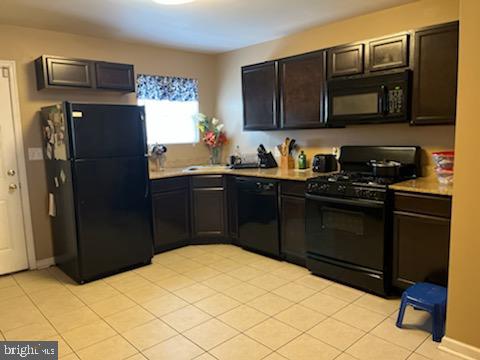 kitchen featuring light tile patterned floors, dark brown cabinetry, and black appliances