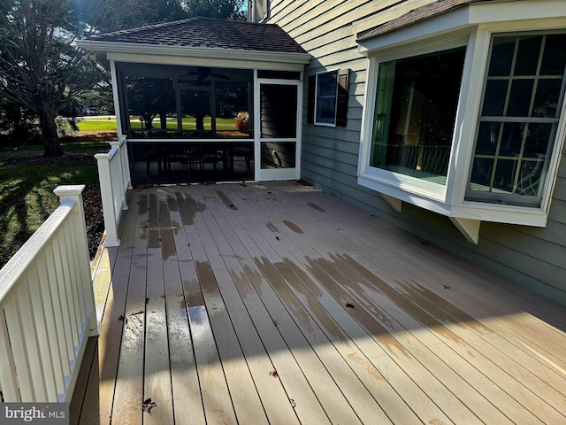 wooden deck featuring a sunroom and ceiling fan