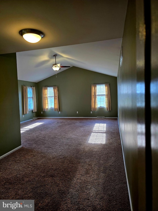 carpeted empty room with lofted ceiling, ceiling fan, and a healthy amount of sunlight