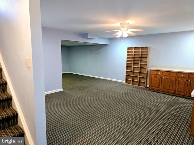 basement featuring dark carpet and ceiling fan