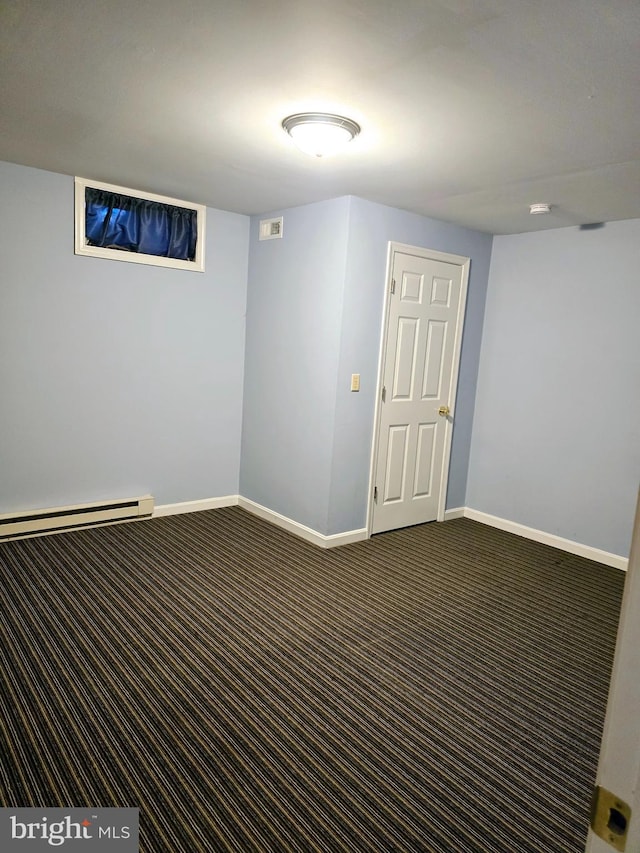 basement featuring dark carpet and baseboard heating