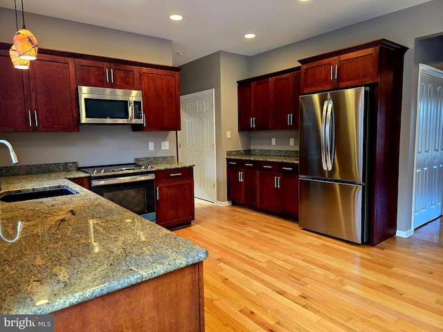 kitchen with pendant lighting, sink, light wood-type flooring, appliances with stainless steel finishes, and light stone counters