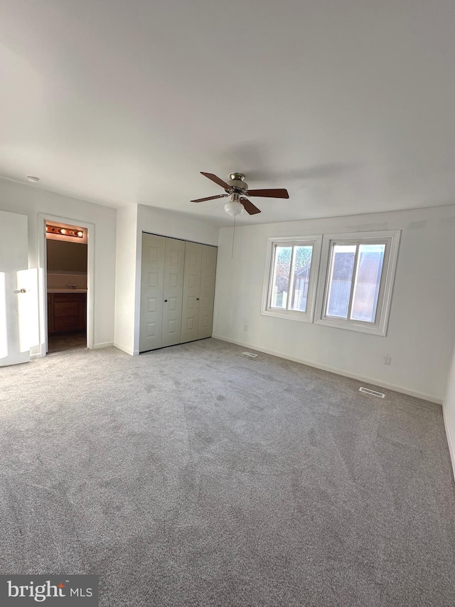 unfurnished bedroom featuring carpet, ceiling fan, and a closet