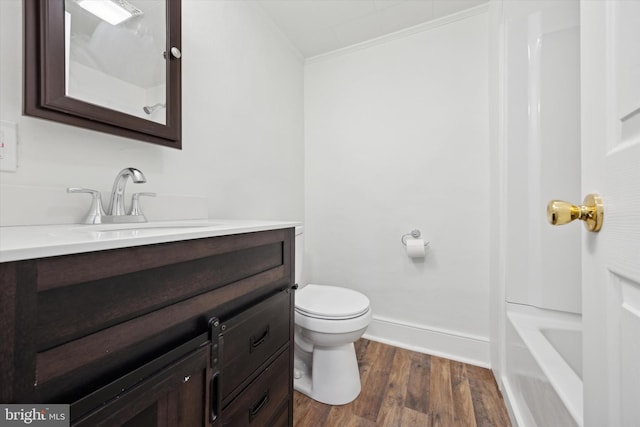 bathroom with wood-type flooring, vanity, toilet, and crown molding