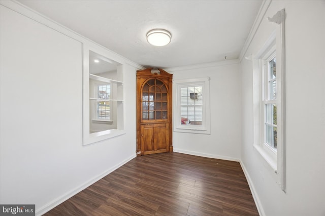 unfurnished dining area featuring plenty of natural light, dark hardwood / wood-style floors, and ornamental molding