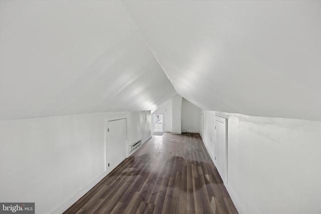 additional living space with a baseboard radiator, dark hardwood / wood-style floors, and vaulted ceiling