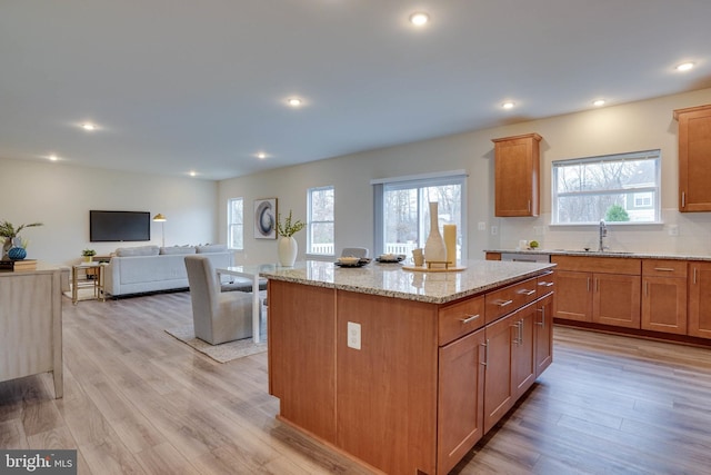 kitchen with light stone counters, a center island, light hardwood / wood-style floors, and plenty of natural light