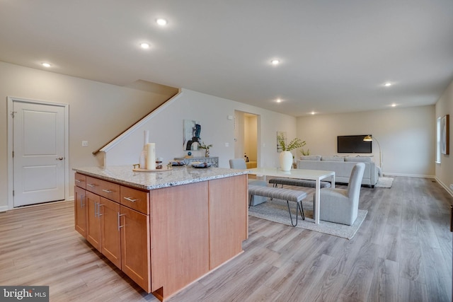 kitchen with light stone countertops, a center island, and light hardwood / wood-style floors