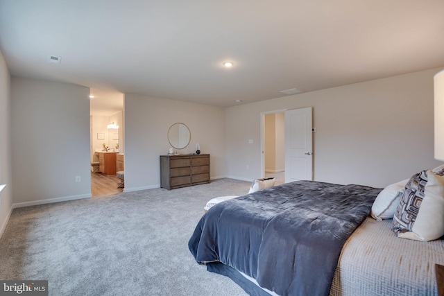 bedroom with ensuite bathroom and light carpet