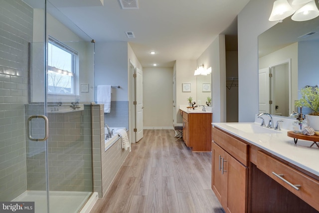 bathroom featuring vanity, wood-type flooring, and shower with separate bathtub