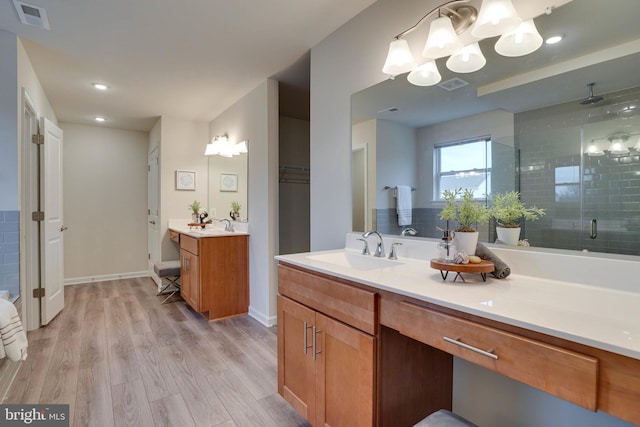 bathroom with hardwood / wood-style floors, vanity, and a shower with door