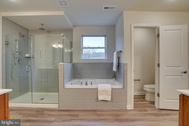 full bathroom with plus walk in shower, vanity, wood-type flooring, and toilet