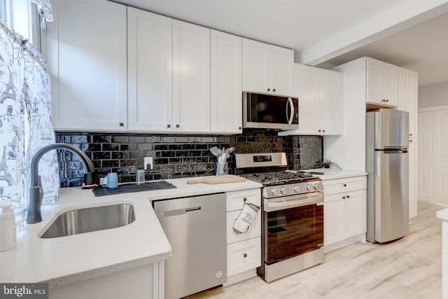 kitchen with light hardwood / wood-style floors, decorative backsplash, sink, appliances with stainless steel finishes, and white cabinets