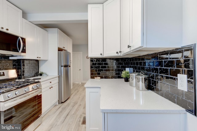 kitchen with appliances with stainless steel finishes, decorative backsplash, and white cabinetry