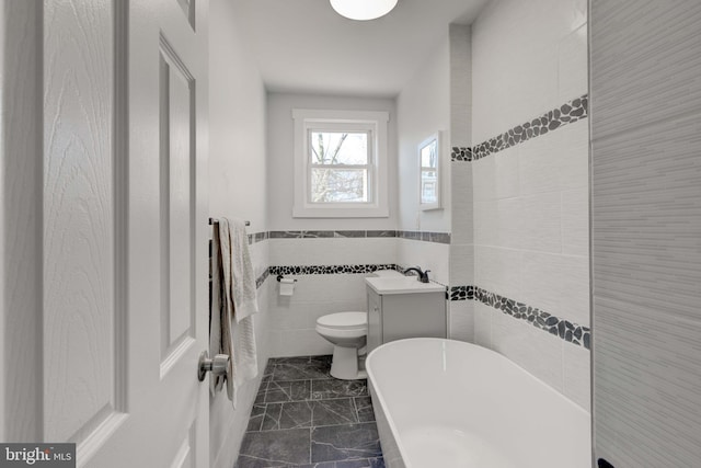 bathroom with toilet, tile walls, a bathtub, and vanity