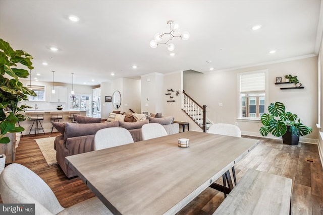 dining room with ornamental molding, hardwood / wood-style floors, and a chandelier