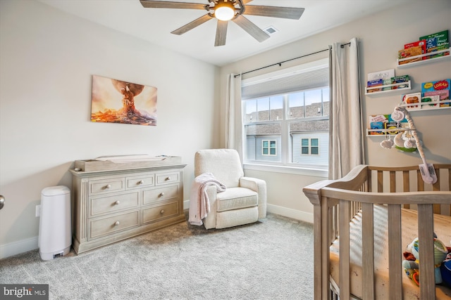 bedroom with light carpet, a nursery area, and ceiling fan