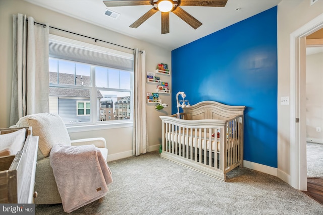 bedroom featuring a crib, ceiling fan, and carpet