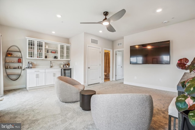 living room with wine cooler, ceiling fan, light colored carpet, and indoor wet bar