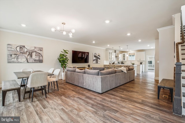 living room featuring wood-type flooring, ornamental molding, and a chandelier