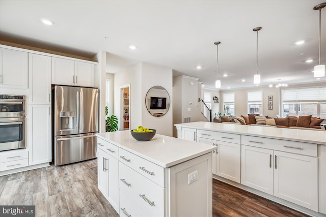 kitchen featuring stainless steel appliances, a center island, hanging light fixtures, and white cabinets