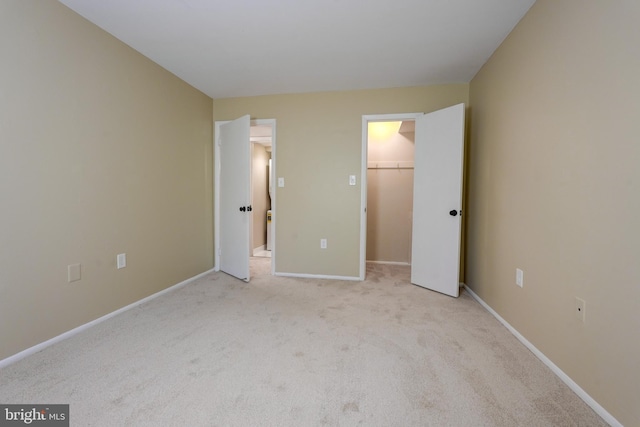 unfurnished bedroom featuring a walk in closet, light carpet, and a closet