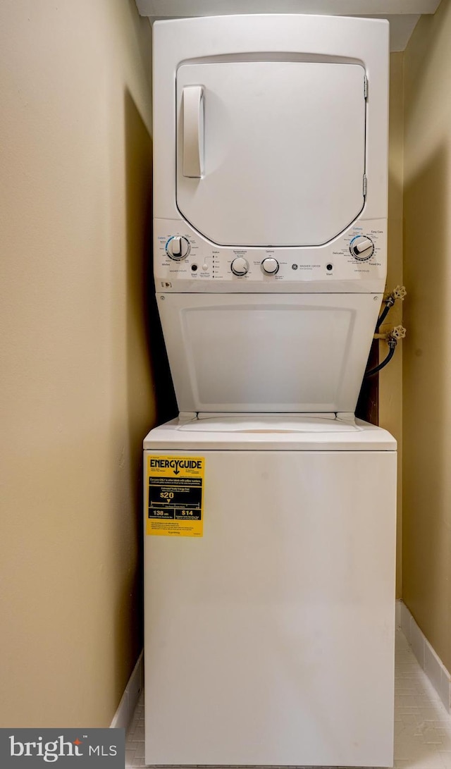 clothes washing area featuring light tile patterned floors and stacked washing maching and dryer