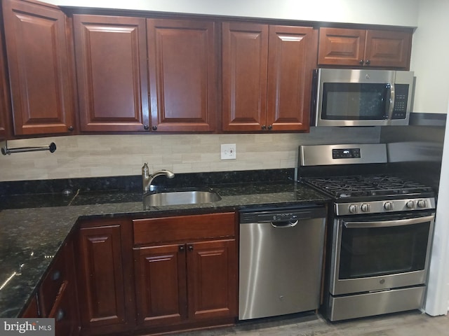 kitchen featuring sink, decorative backsplash, dark stone countertops, appliances with stainless steel finishes, and light hardwood / wood-style floors