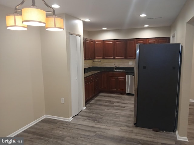 kitchen featuring pendant lighting, sink, decorative backsplash, appliances with stainless steel finishes, and dark hardwood / wood-style flooring