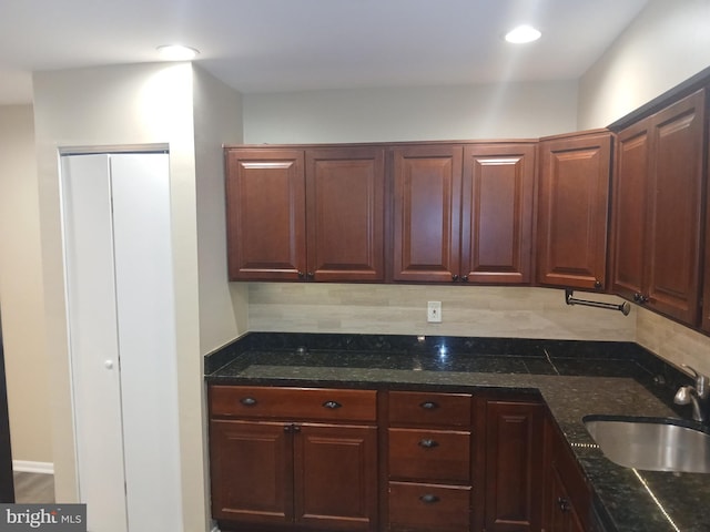 kitchen featuring decorative backsplash, dark stone countertops, and sink