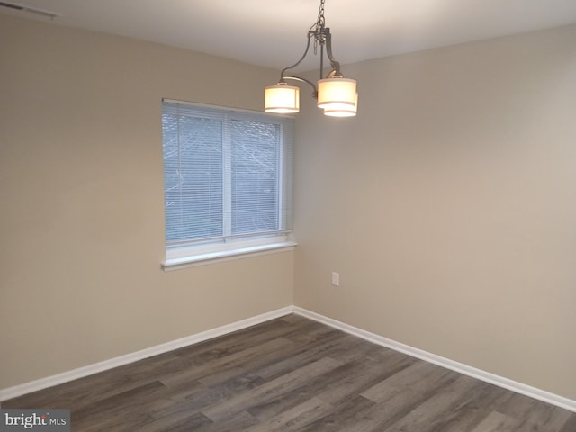 unfurnished dining area featuring dark wood-type flooring and a notable chandelier