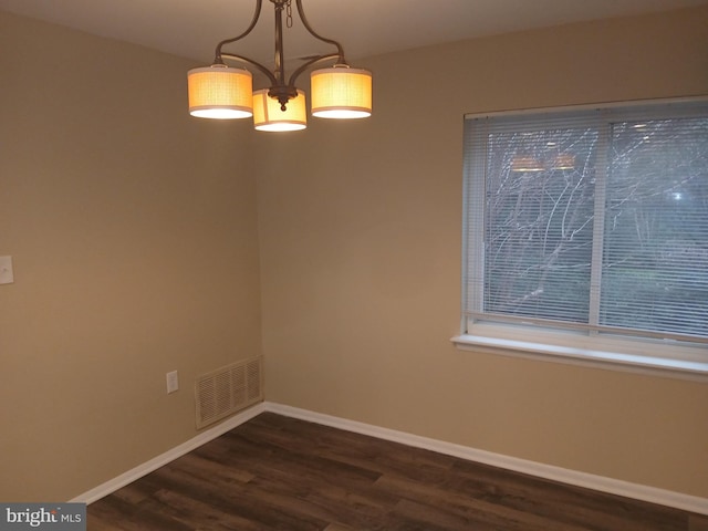 unfurnished dining area with dark hardwood / wood-style flooring and an inviting chandelier