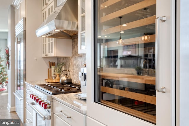 kitchen featuring appliances with stainless steel finishes, white cabinetry, wine cooler, light stone countertops, and decorative backsplash