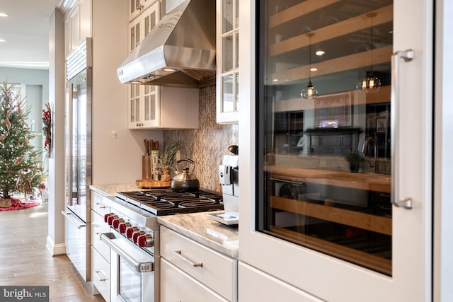 kitchen featuring white cabinetry, tasteful backsplash, light stone counters, light hardwood / wood-style flooring, and premium appliances