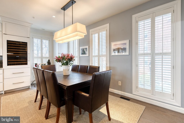 dining area with a wealth of natural light, wine cooler, and light hardwood / wood-style flooring