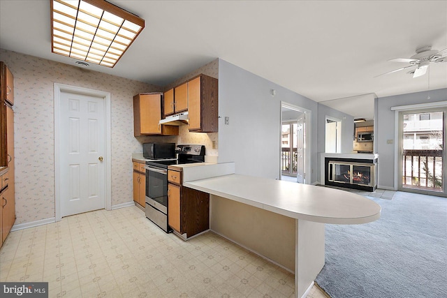 kitchen featuring a kitchen breakfast bar, ceiling fan, light colored carpet, kitchen peninsula, and stainless steel appliances