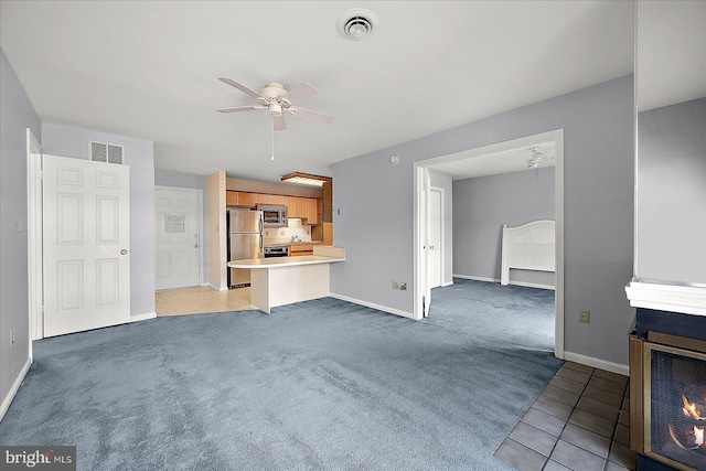 unfurnished living room featuring ceiling fan and light carpet