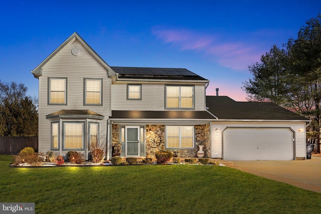 front of property with solar panels, a yard, and a garage