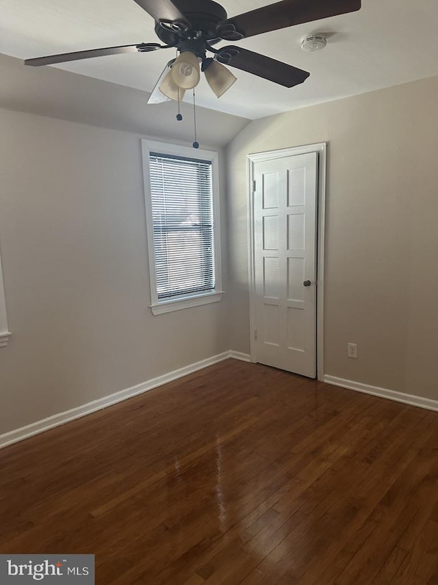 empty room with vaulted ceiling, ceiling fan, and dark wood-type flooring