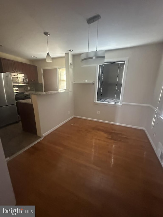 kitchen with kitchen peninsula, appliances with stainless steel finishes, dark hardwood / wood-style flooring, and hanging light fixtures