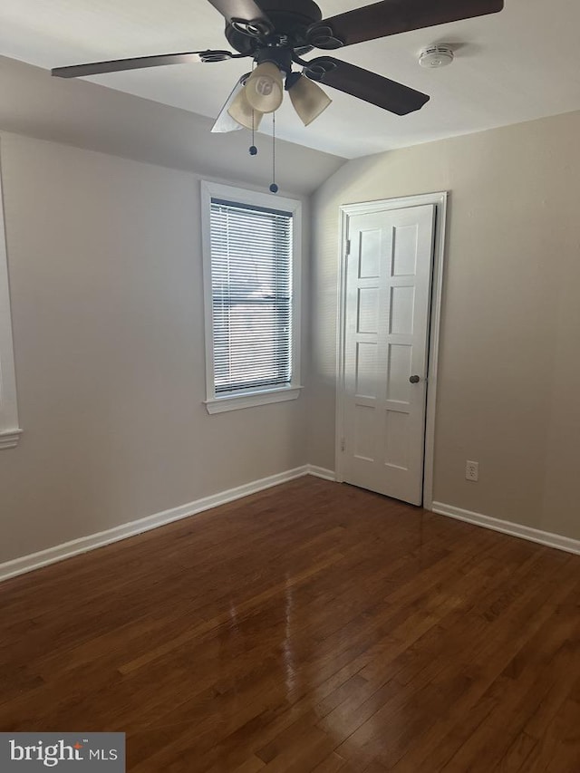 unfurnished bedroom with vaulted ceiling, ceiling fan, a closet, and dark hardwood / wood-style floors